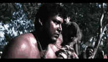 a man with red paint on his face is standing in the woods with other people .