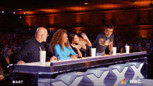 a group of people are sitting at a table with a nbc logo on it