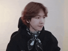 a young man wearing headphones and a scarf around his neck is looking at the camera .