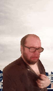 a man with glasses and a beard takes off his shirt