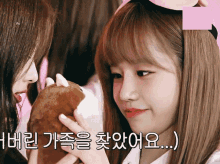 a girl holding a stuffed animal next to another girl with korean writing on the bottom