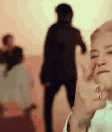 a woman is clapping her hands in front of a group of people in a room .