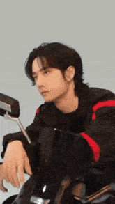a young man is leaning on a black motorcycle