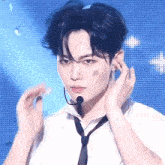 a man wearing a tie and a microphone adjusts his hair