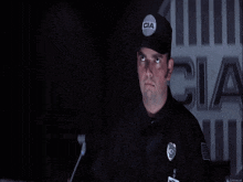 a man wearing a cia hat is pointing at his head