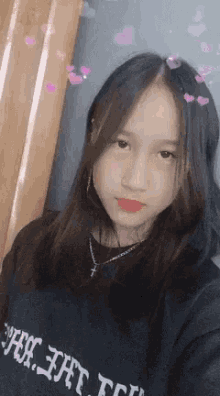 a young girl wearing a black shirt and a necklace is taking a selfie .