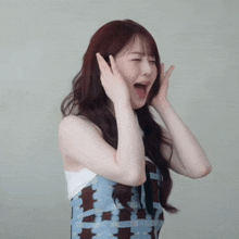 a woman is covering her ears with her hands and making a funny face