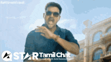 a man wearing sunglasses is standing in front of a star tamil chat logo