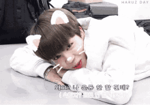 a boy with a cat ear on his head laying on the floor