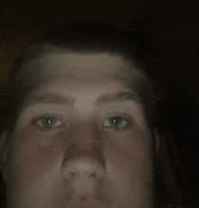 a close up of a young man 's face with a dark background
