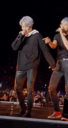 two men singing into microphones on a stage