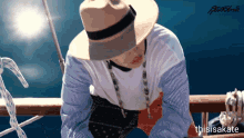 a man wearing a hat and a striped shirt is sitting on a boat with the words thisisakate written below him