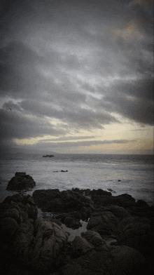 a cloudy sky over a body of water with rocks
