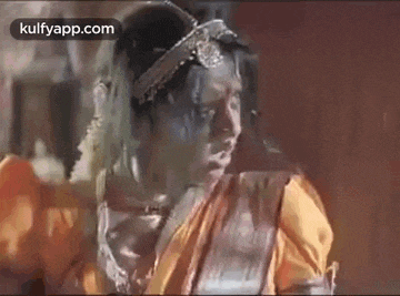 a woman in a costume is standing in front of a wooden wall and looking at the camera .