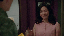 a woman is crossing her fingers in front of a mirror while a man looks on .