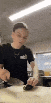 a woman is cutting a cucumber on a cutting board