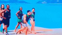 a group of people are running on a beach in front of the ocean .
