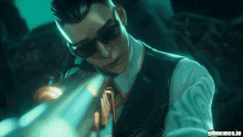 a man in a suit and tie is holding a gun with gifmemes.io written in the corner
