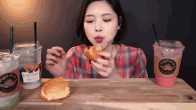 a woman is eating a croissant next to two cups of coffee from angel jesus