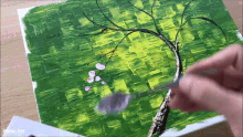 a person is painting a tree with pink flowers on it