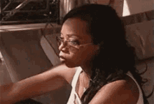 a woman wearing glasses is sitting on a couch looking at something .