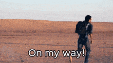 a man with a backpack is walking in the desert with the words on my way below him