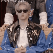 a man wearing sunglasses and a jacket with the number 412,871 on the top