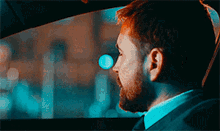 a man with a beard is driving a car at night
