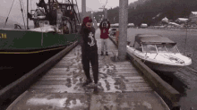 a group of people standing on a dock next to boats .