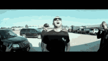 a man wearing sunglasses is standing in a parking lot with other men