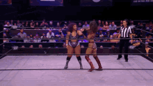 two women are in a wrestling ring with a referee and a sign that says live on pay per view