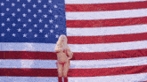 a woman in a bikini stands in front of a large american flag