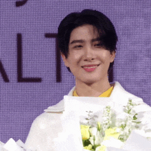 a man holding a bouquet of flowers in front of a purple background