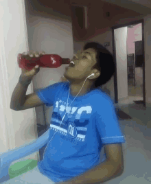 a boy wearing a blue shirt with the number 01 on it is drinking from a red bottle