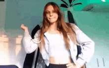 a woman wearing a crop top and a hoodie is standing in a room .