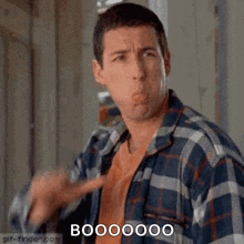 a man in a plaid shirt is making a funny face while pointing at something .