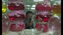 a man is pointing a gun at a display of pink candy