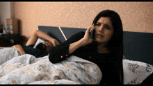 a woman is talking on a cell phone while a man sleeps in the background