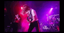 a man is playing a guitar on stage in front of a drum set with the word the on it