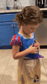 a little girl in a snow white costume is playing with a toy