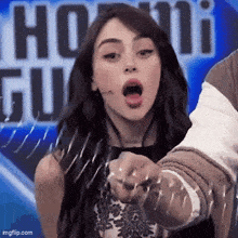 a woman is pointing at the camera with her mouth open in front of a sign that says ' ho ' on it