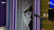 a woman is standing in front of a microphone with idol radio written on the screen behind her