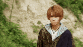 a young man wearing a necklace and a sweater with a geometric pattern