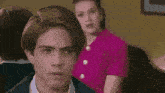 a woman in a pink shirt and earrings is talking to someone .