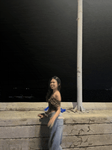 a woman in a leopard print top and jeans is standing next to a pole