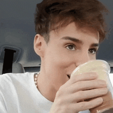 a young man drinking from a plastic cup with his mouth open