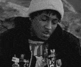 a black and white photo of a man wearing a hat and a hoodie .