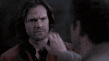a person is touching a man 's face with their hand .