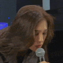 a woman is holding a shure microphone in her hand and talking into it .