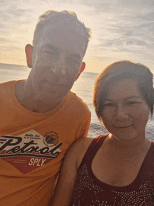 a man and a woman are posing for a picture and the man is wearing a petrol shirt